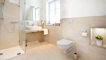 Un baño moderno con cabina de ducha de vidrio, lavamanos, inodoro y espejo.
