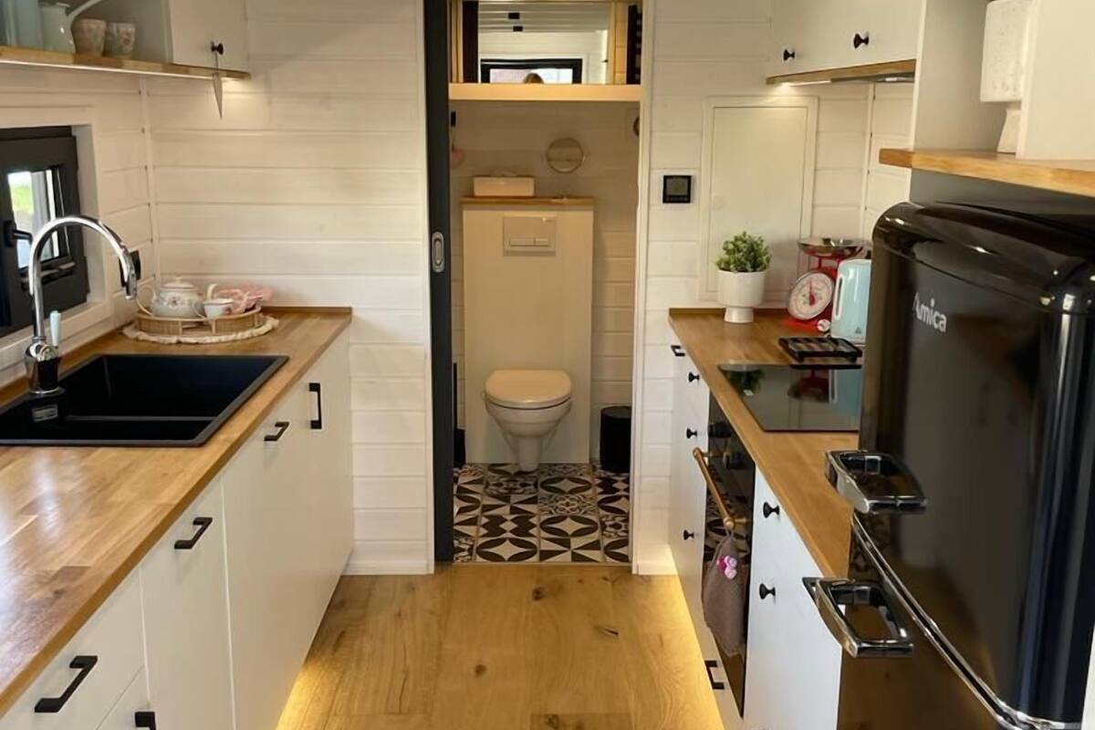 A compact kitchen with wooden countertops, a black refrigerator, and a small sink.