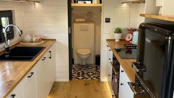 A compact kitchen with wooden countertops, a black refrigerator, and a small sink.