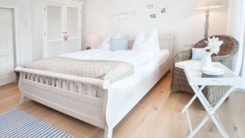 Una camera da letto ordinata con un letto, un comodino, una lampada e una sedia in vimini.