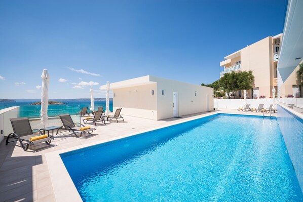 Piscine extérieure en saison, parasols, chaises longues