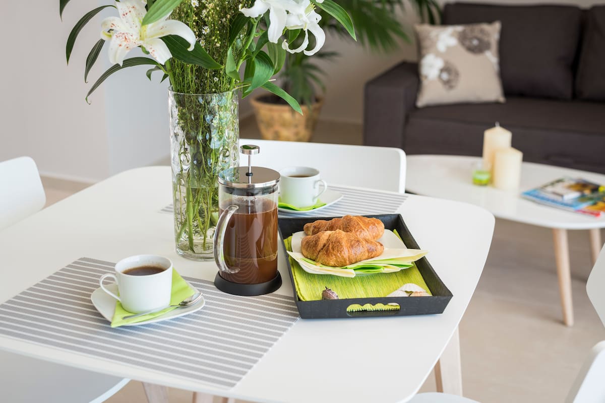 A dining table with a coffee cup, a glass of water, and a tray with croissants.