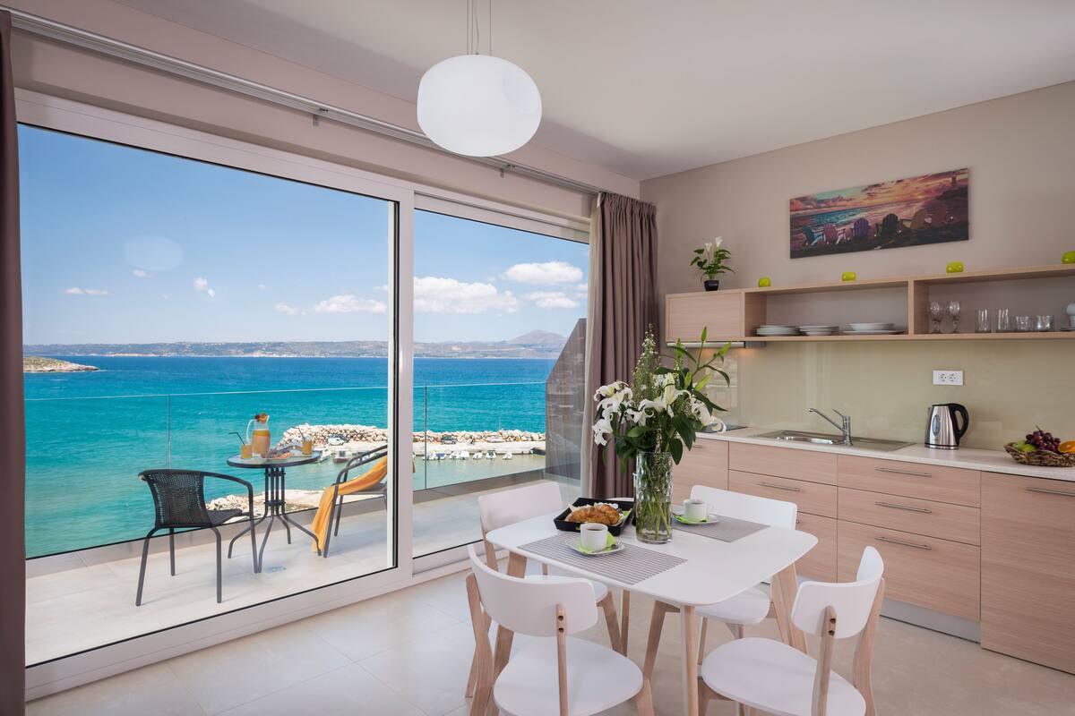 A modern kitchen with a large window overlooking a scenic ocean view.