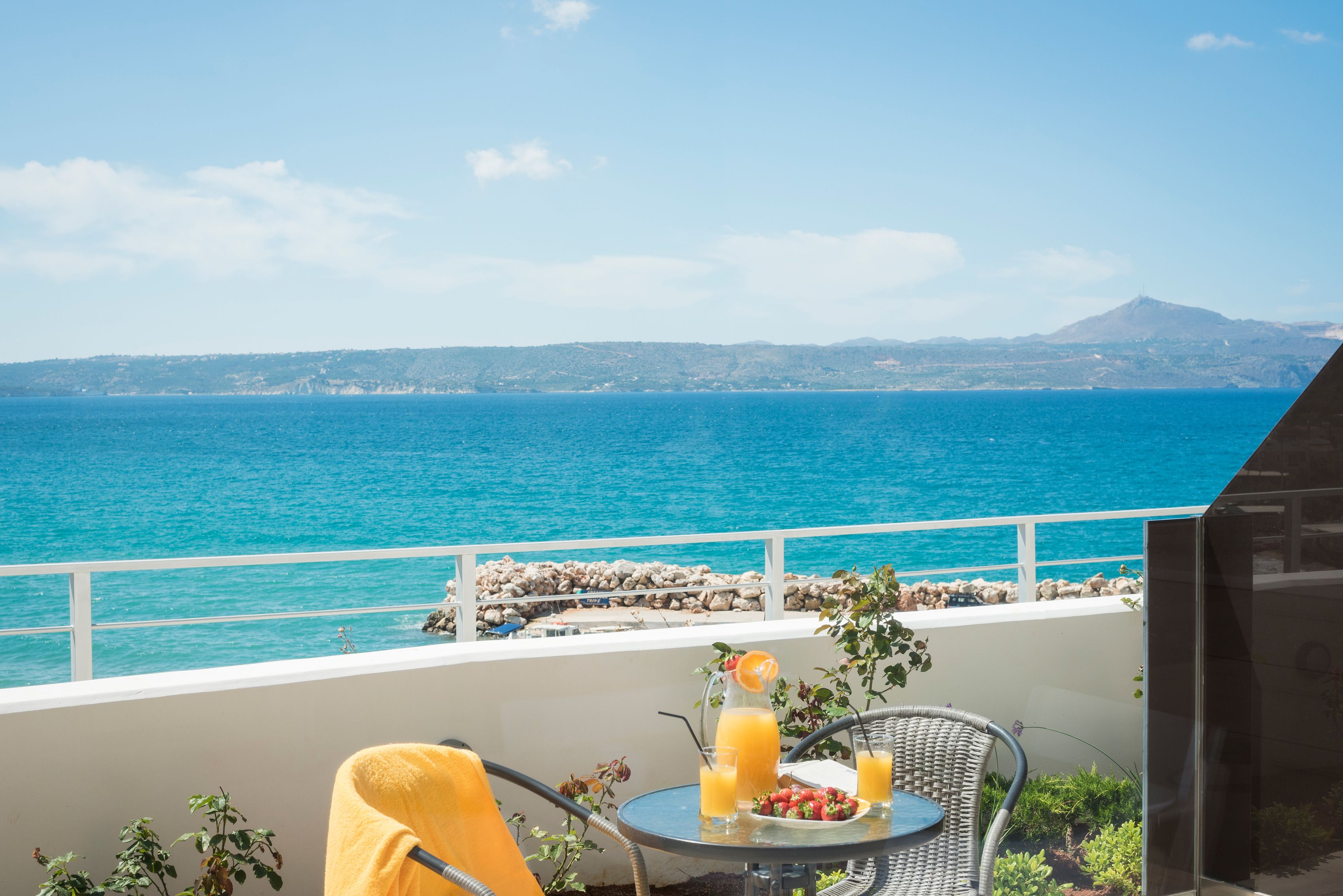 Un balcón con mesa, sillas y vista al mar.