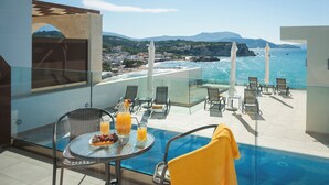 A balcony with a pool, chairs, and a table with fruit and drinks. - Panorama Plus (Apokoronas)