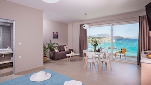 A modern hotel room with a balcony, a sofa, a dining table, and a view of the sea. - Panorama Plus (Apokoronas)