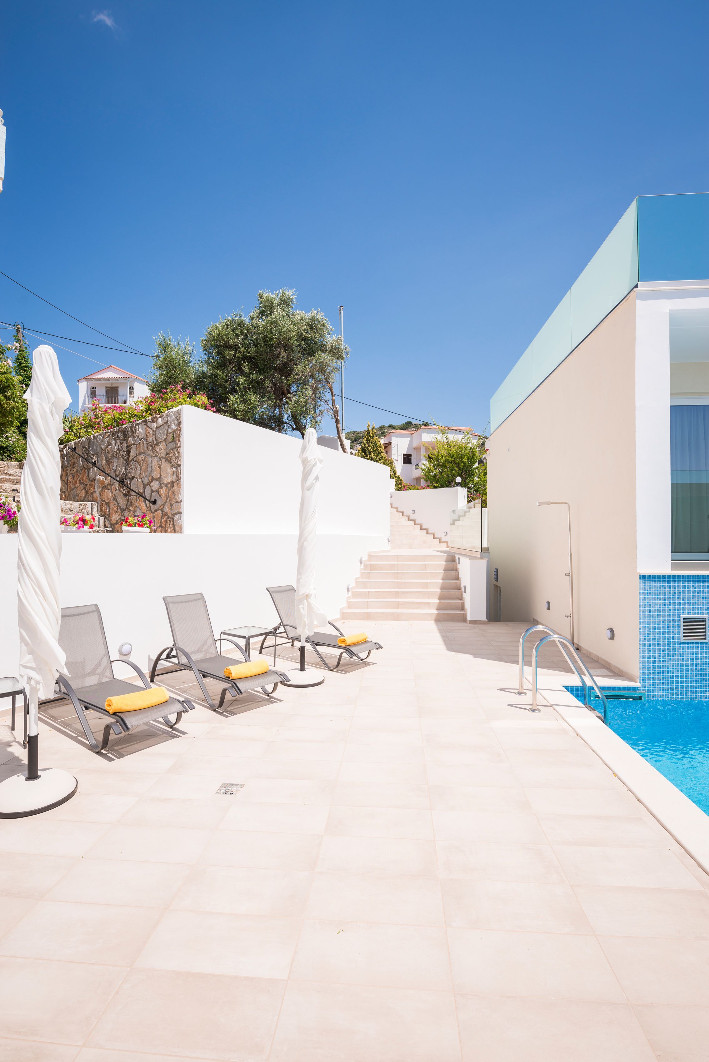 A poolside area with sun loungers, a small pool, and a staircase leading to a building.