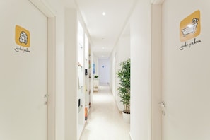 A hallway with white walls and doors, each marked with a logo and name. - Palermo Central B&B (Palermo)