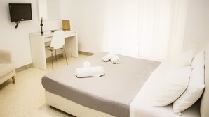 A hotel room with a bed, a desk, a chair, a TV, and a window with curtains. - Palermo Central B&B (Palermo)