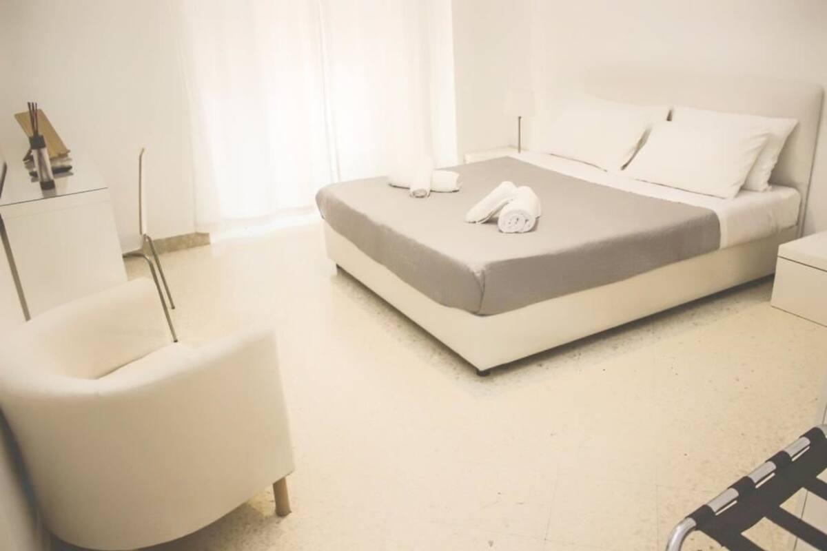 A modern hotel room with a bed, a chair, and a small table.