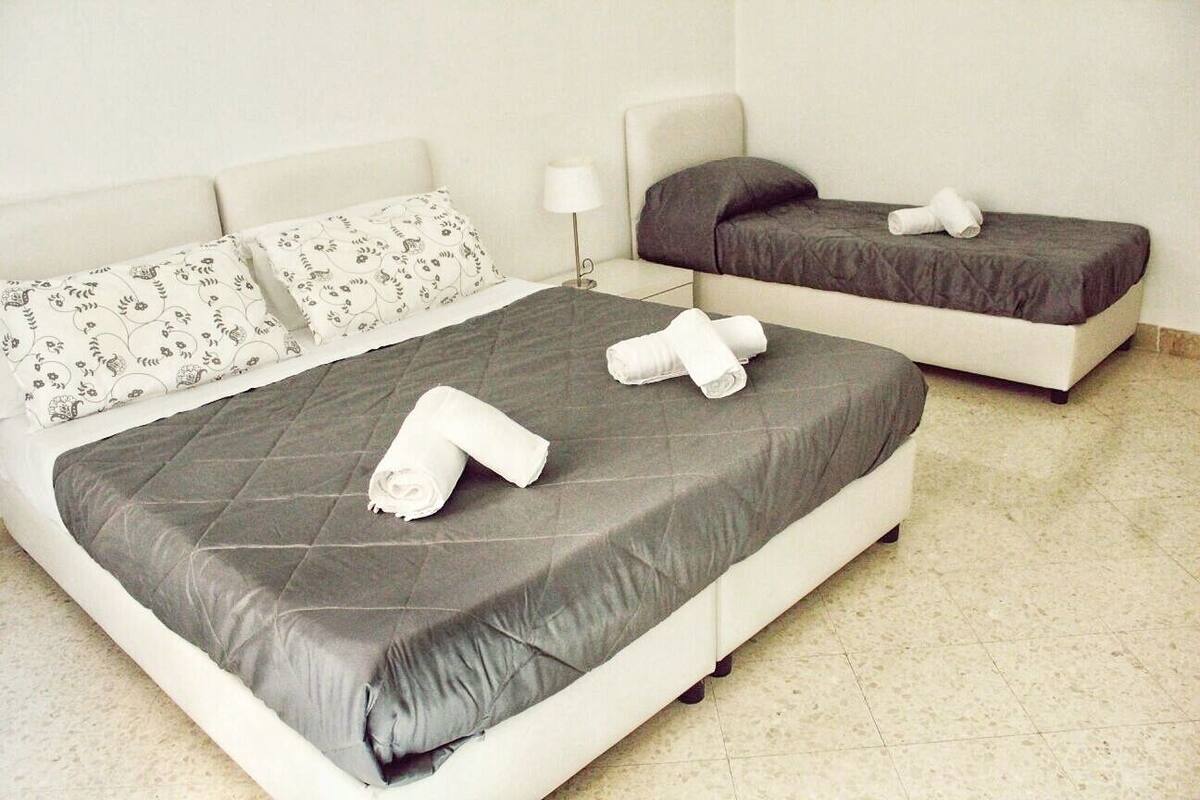 A hotel room with a large bed, a smaller bed, and a nightstand with a lamp.