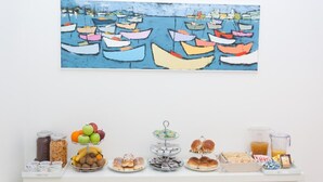 A buffet table with various food items and a colorful painting of boats on the wall above. - Palermo Central B&B (Palermo)