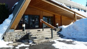 Um edifício com telhado inclinado e entrada de madeira.