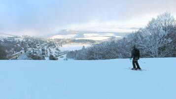 A person skiing on a snowy slope with a town and mountains in the background.