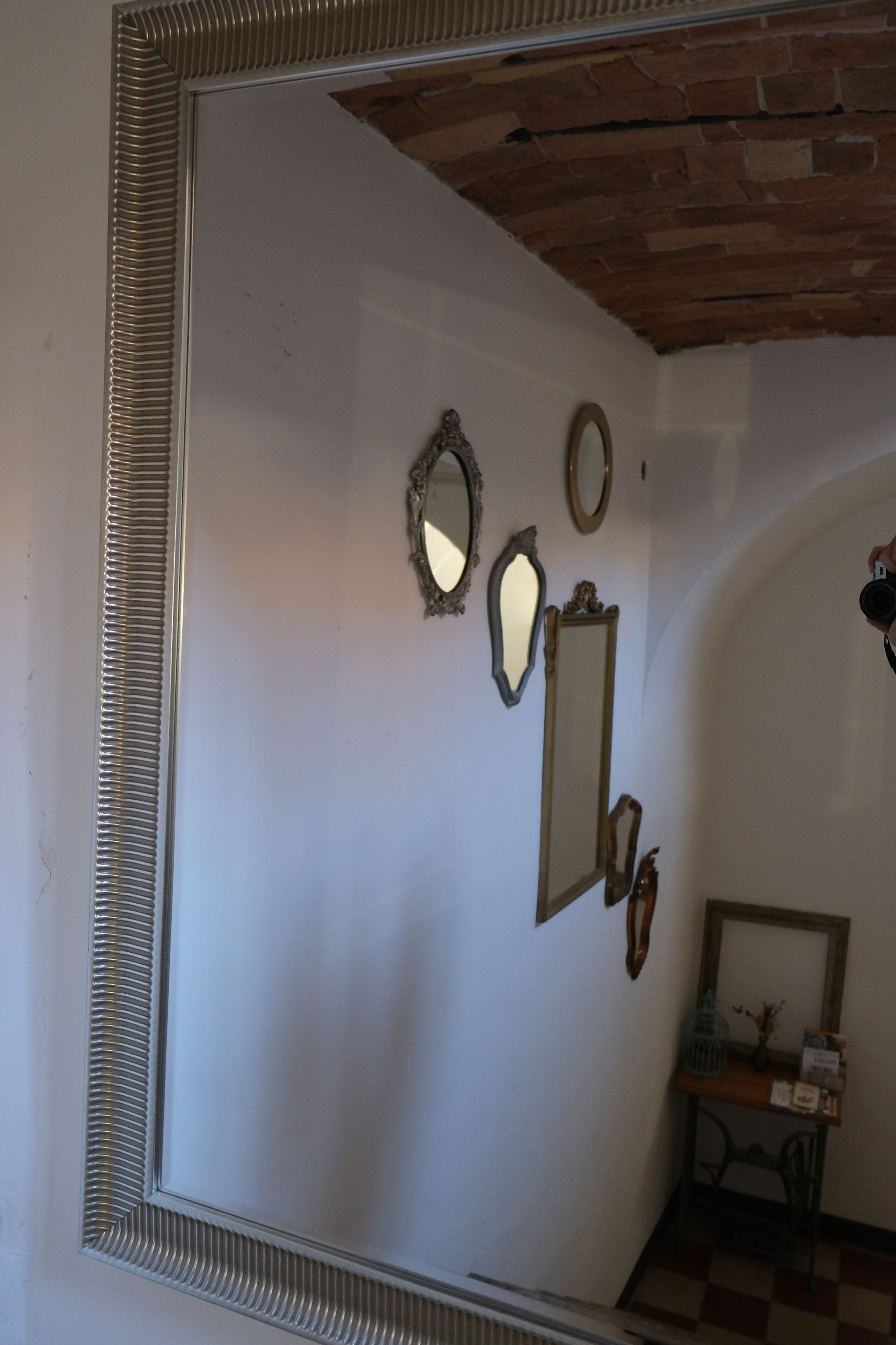 Una habitación con un espejo grande, varios espejos más pequeños y un suelo a cuadros.
