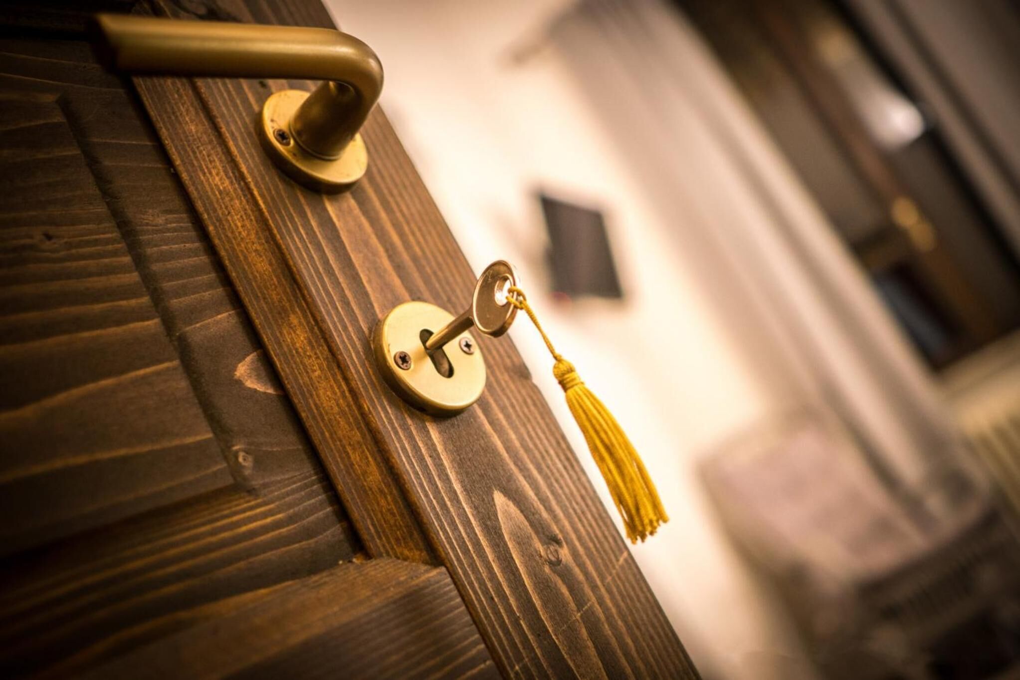 A close-up of a brass door handle with a keyhole and a tassel.