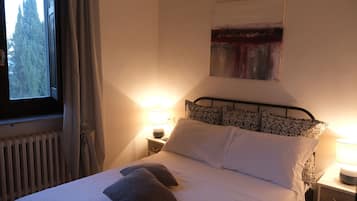 A neatly made bed with pillows, a bedside lamp, and a window with curtains.