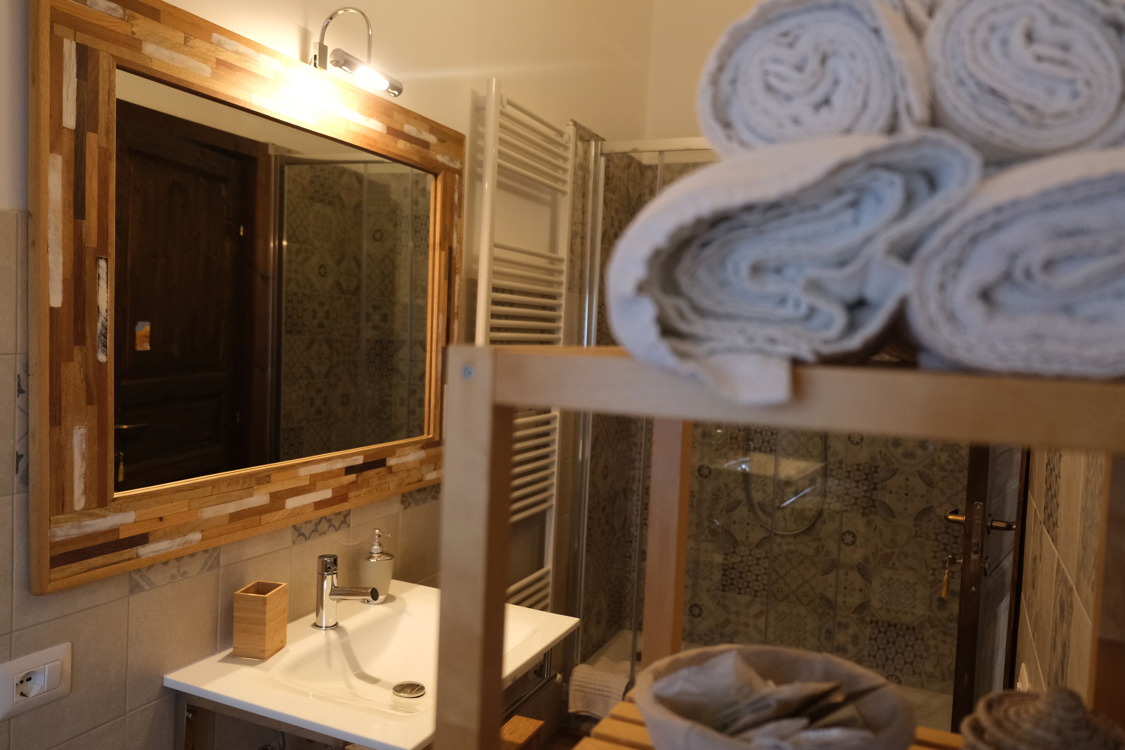 A bathroom with a wooden vanity, a sink, a mirror, and a shower area.