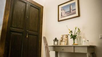 Ein Zimmer mit Holztür, Schreibtisch mit Stuhl, einem gerahmten Bild an der Wand und einer Vase mit Blumen.