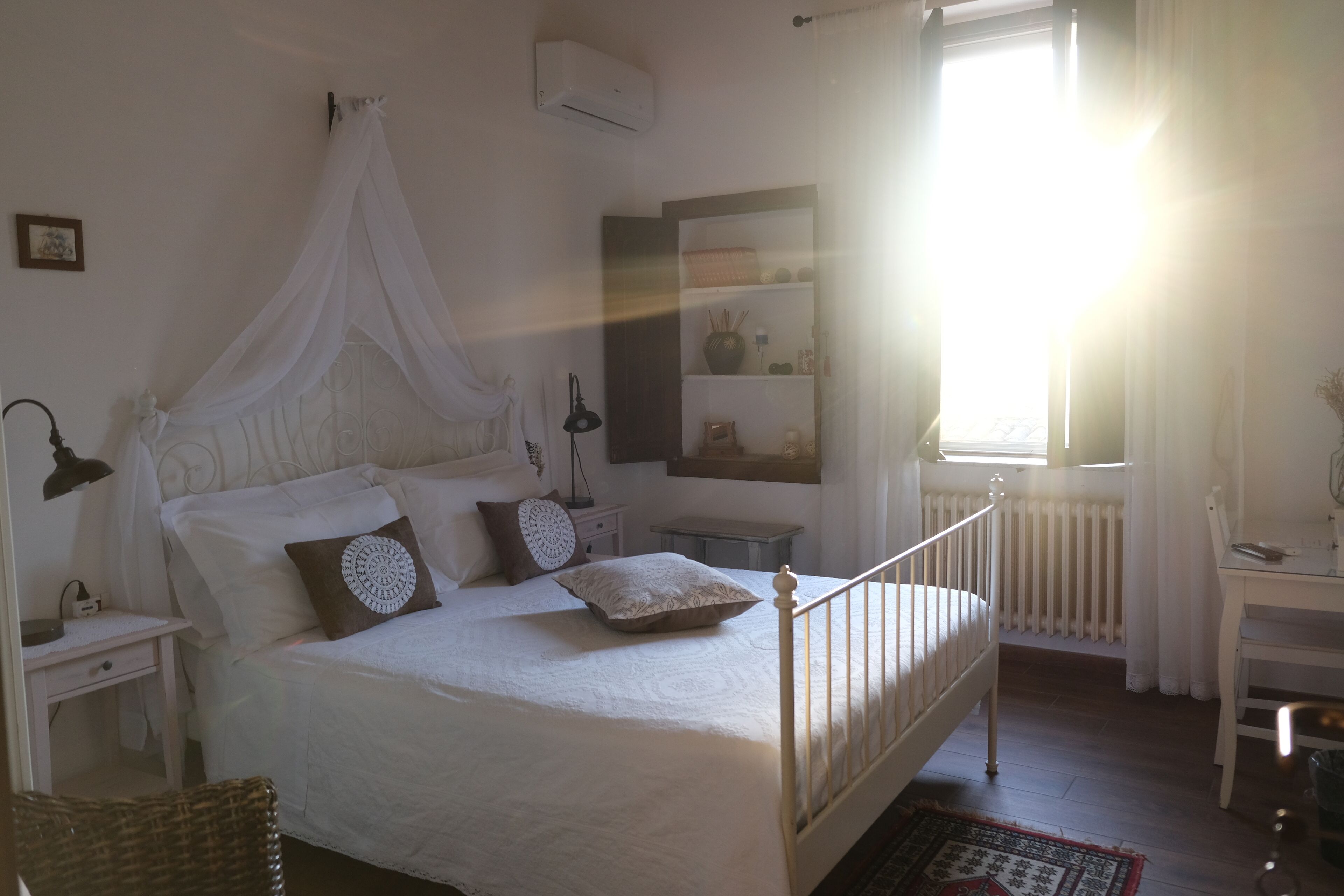 Un dormitorio con cama a dosel, mesitas de noche, un escritorio y un radiador.