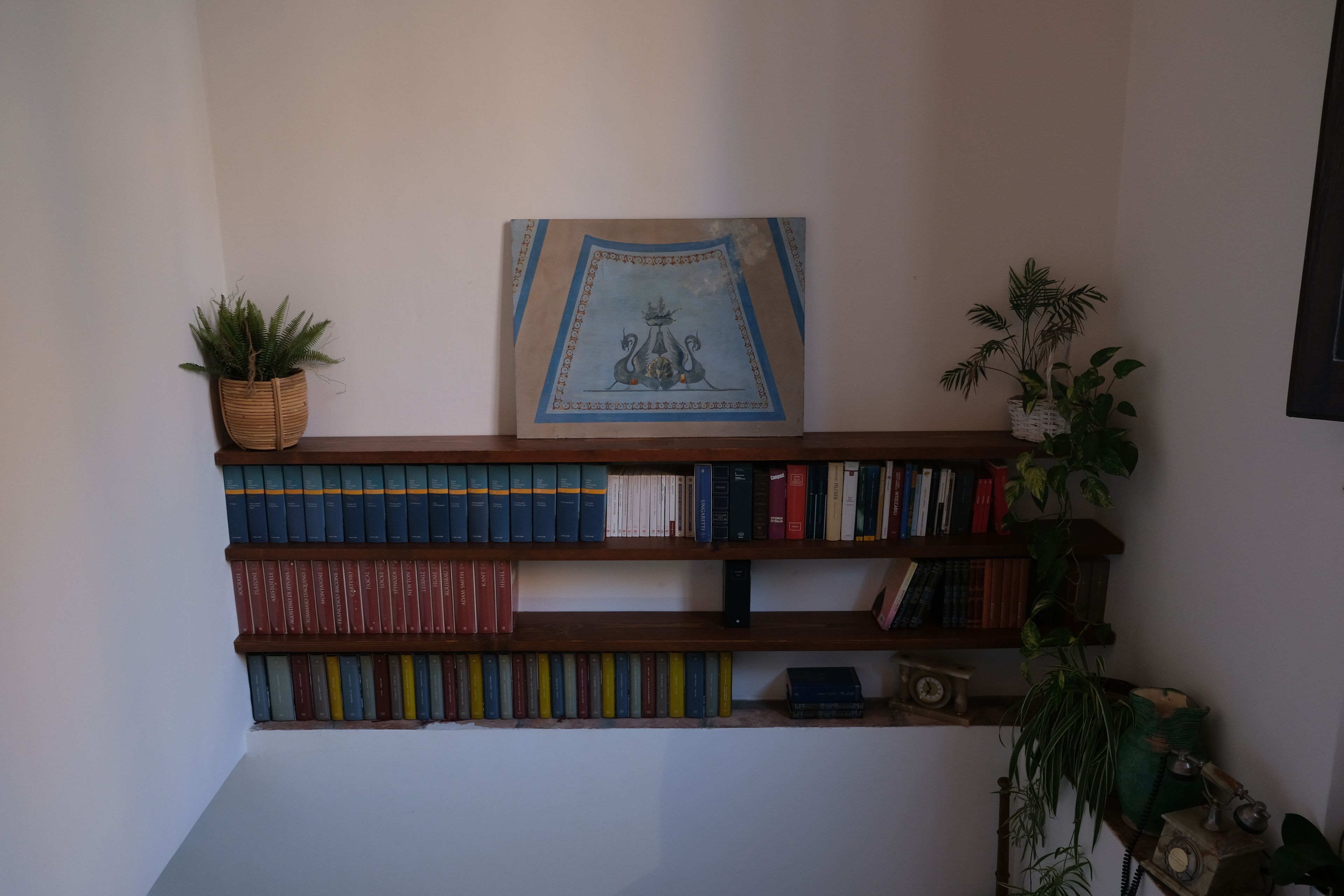 Una estantería con libros y un cuadro en la pared.