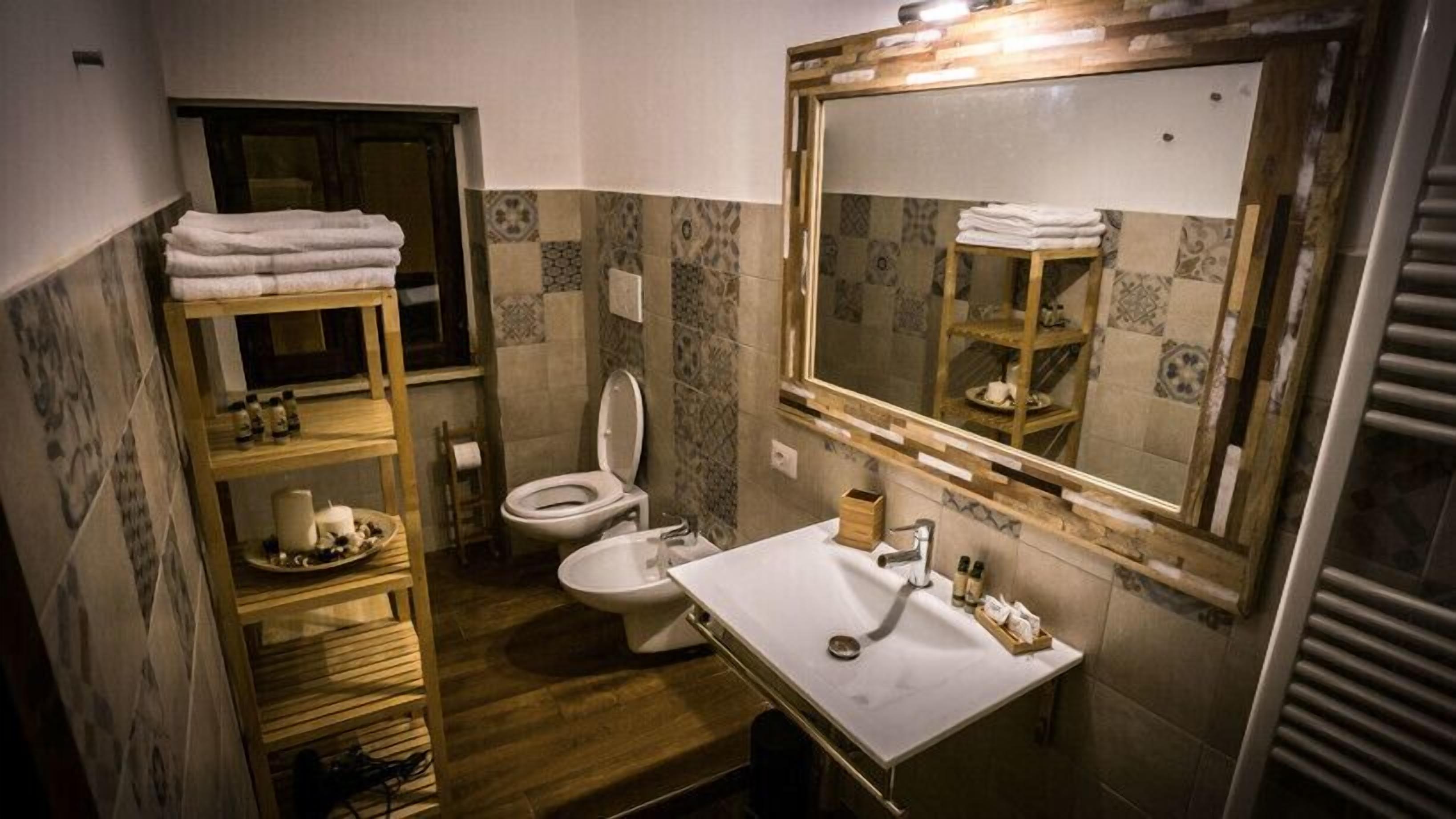 Un baño pequeño con inodoro, lavamanos y estantes de madera.