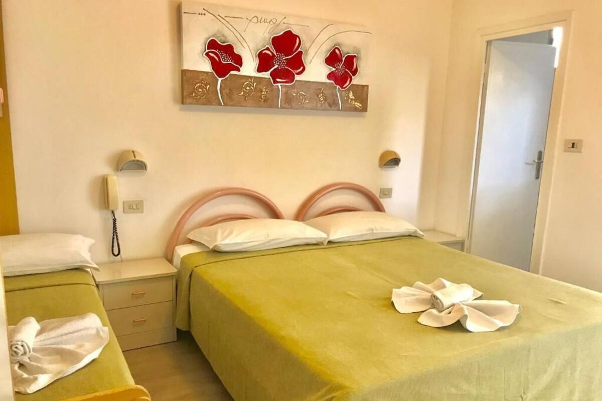 A hotel room with two beds, a telephone, a wall art piece, and a door.