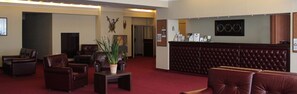 Un hall d’entrée avec des sièges en cuir, un comptoir de réception et un téléviseur.