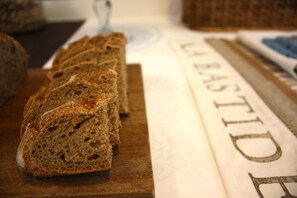 Slices of whole grain bread on a wooden board, with a cloth displaying the text "LA BASTID". - Hotel Il Perugino (Corciano)