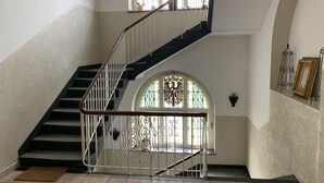 A staircase with a white railing, a stained glass window, and a wall-mounted light fixture. - Hotel Rathaus 1910 (Essen)