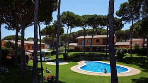 A pool area with a clear blue pool, surrounded by well-maintained grass and trees. - Casas Golf Relax (Pals)
