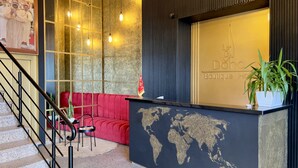 Un espace d’accueil avec un canapé rouge, une carte du monde sur le comptoir et un drapeau.