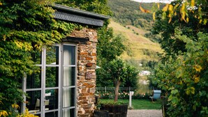 Un edificio de piedra con puerta de cristal, rodeado de vegetación y un sendero de grava.