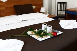 A neatly made bed with white linens, a tray with condiments and a rose, and a chair and table in the background. - Darius Firenze B&B (Florence)