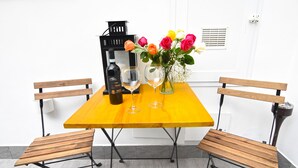 Et træbord med to bænke, en vinflaske, to vinglas og en vase med blomster.