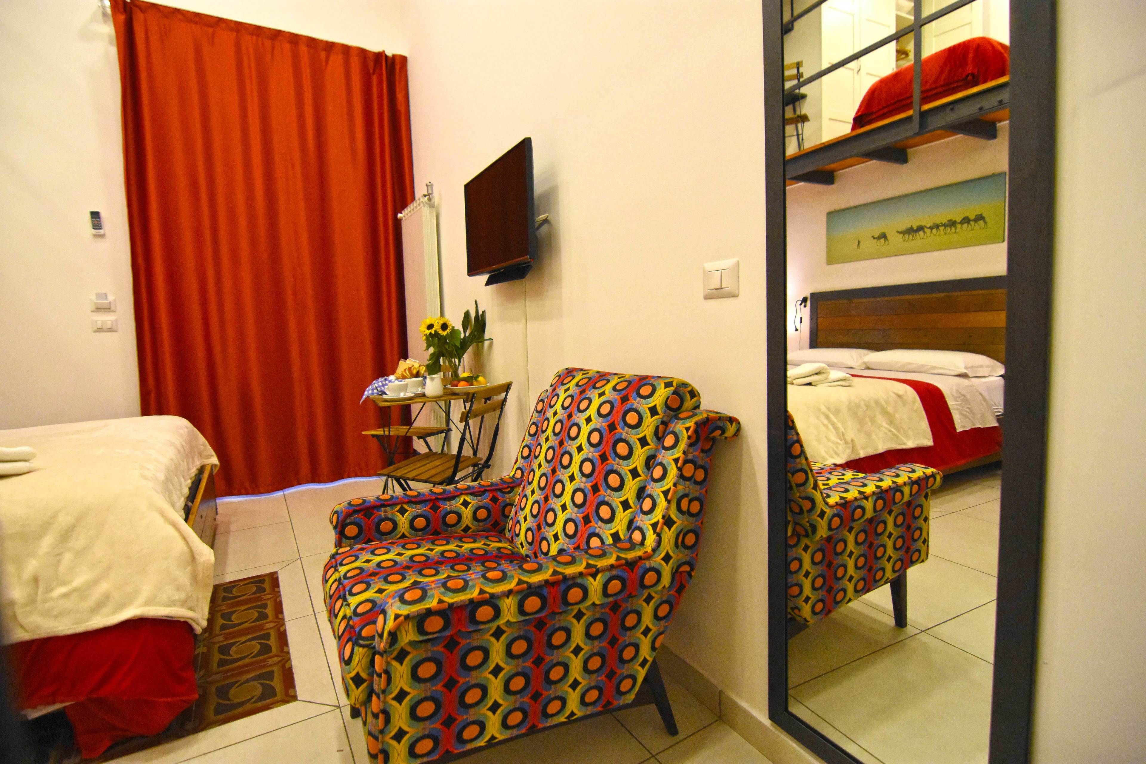 A room with a bed, a chair, a TV, and a mirror.