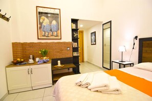 Une chambre d’hôtel avec un lit, une petite table avec une lampe, une bibliothèque et un mur en briques.