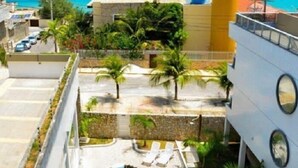 A hotel with a rooftop pool, a view of the ocean, and a tall cylindrical structure. - Happy Hotel Ponta Negra (Natal)