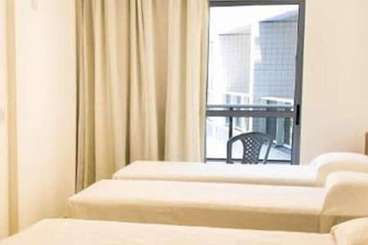 A hotel room with two beds, a window with a view of buildings, and a chair outside the window.