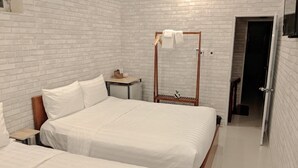 A hotel room with two beds, a wooden headboard, a small bedside table, and a wardrobe with a mirror. - Shell Hotel Condao (Ho Chi Minh City)