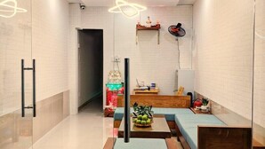 A modern living room with a glass partition, a sofa set, a coffee table with fruit, and a decorative wall piece. - Shell Hotel Condao (Ho Chi Minh City)