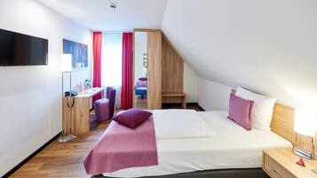 Une chambre d’hôtel moderne équipée d’un grand lit, d’un bureau, d’une chaise et d’un téléviseur.