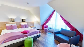 Una habitación de hotel moderna con una cama grande, un sofá, un reposapiés verde y una mesita.