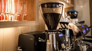 A coffee machine with a coffee bean hopper, a milk frother, and a cup of coffee on the counter.