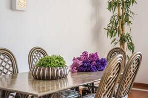 Ett matbord med stolar, en krukväxt och en dekorativ vas med blommor.