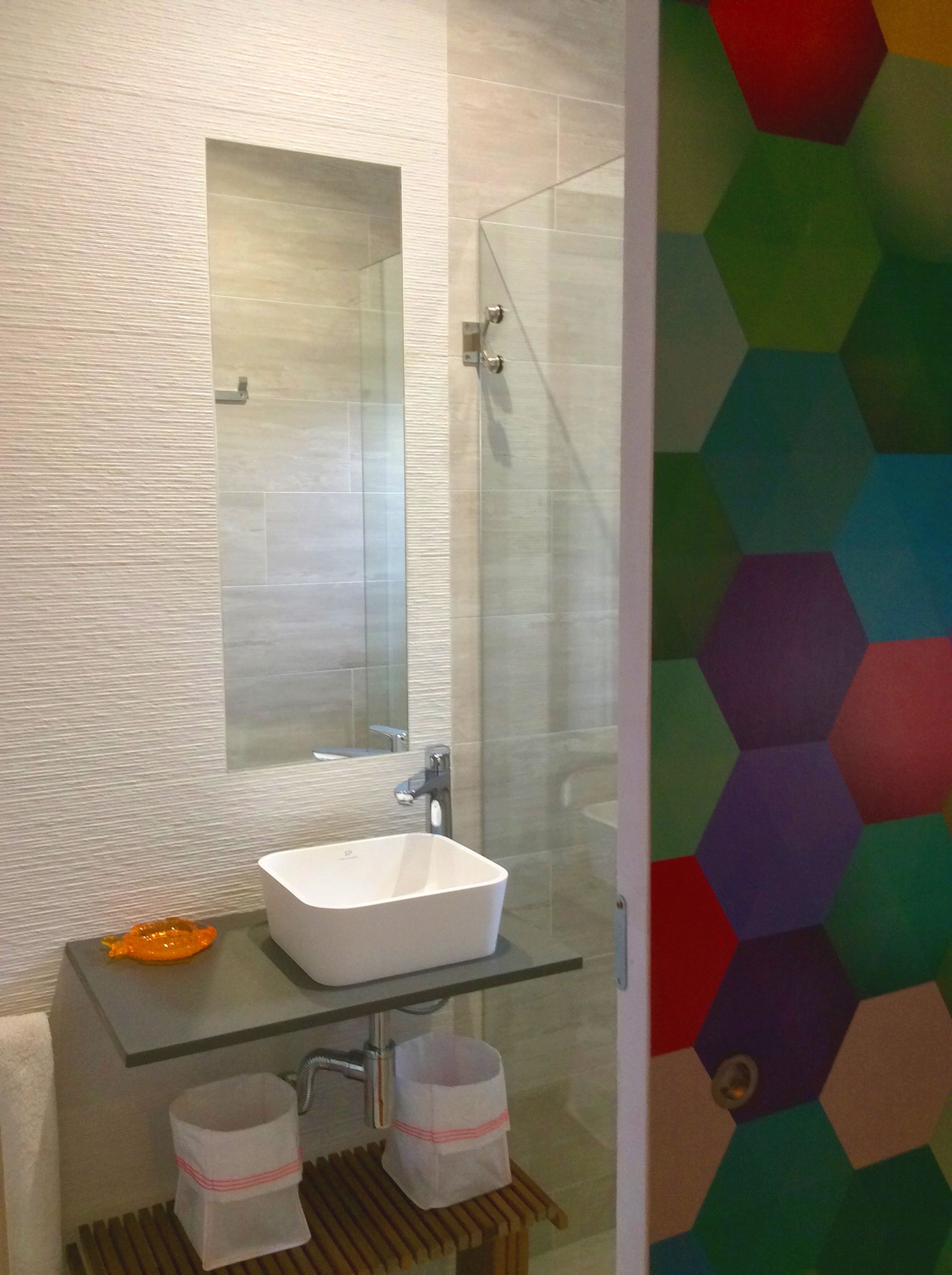 A modern bathroom with a glass sink, a large mirror, and a shower enclosure.