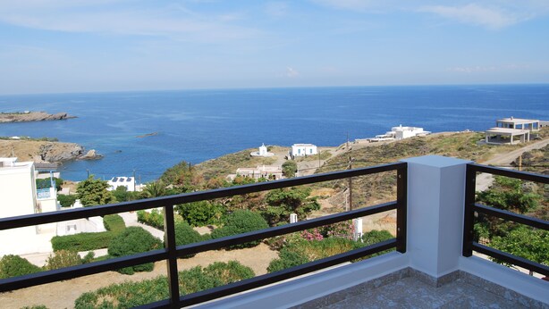 Une vue sur la côte, prise depuis un balcon doté d’une balustrade, donnant sur la mer, des bâtiments et de la végétation.
