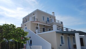 Un bâtiment à deux étages, à l’extérieur blanc, doté d’un espace extérieur abrité et d’un escalier menant à l’étage supérieur.
