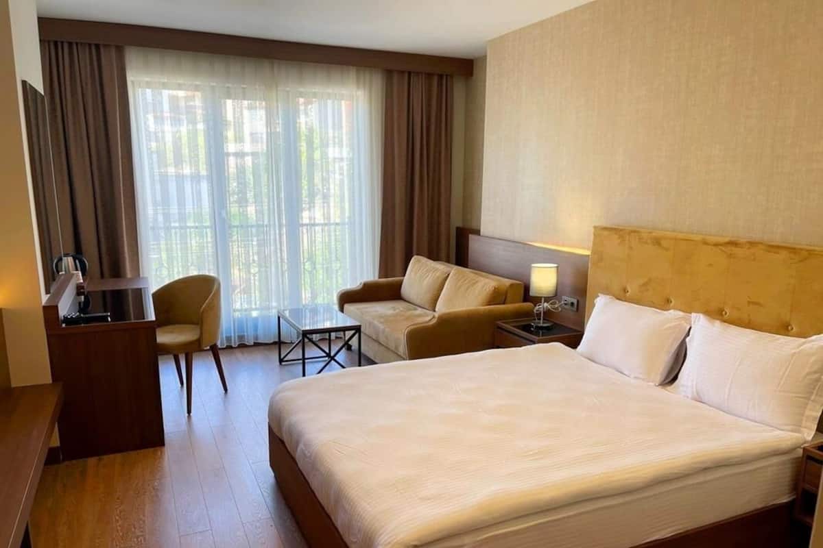 Ett hotellrum med en stor säng, ett skrivbord, en stol och ett litet bord.