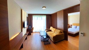 A hotel room with a sofa, a small table, a TV, and a bed.